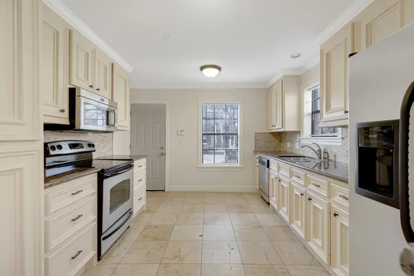 a kitchen with stainless steel appliances granite countertop a stove top oven a sink a counter space and cabinets