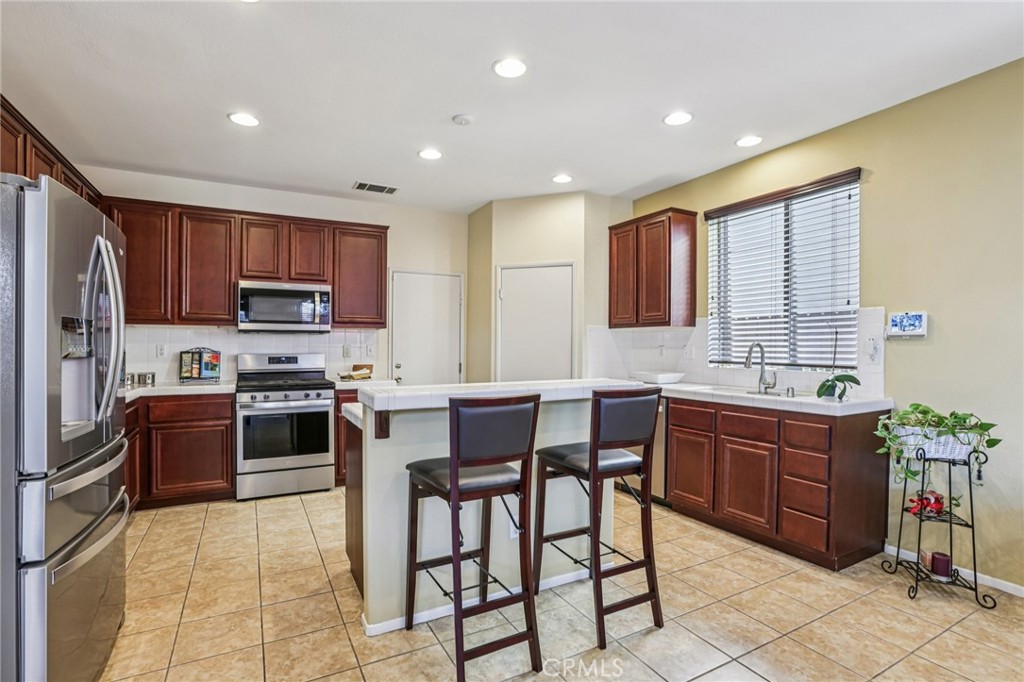 17550 Buttonwood Lane Carson, CA 90746 - Photo 11 of 43 a kitchen with stainless steel appliances granite countertop a stove a sink dishwasher a refrigerator and a dining table with chairs