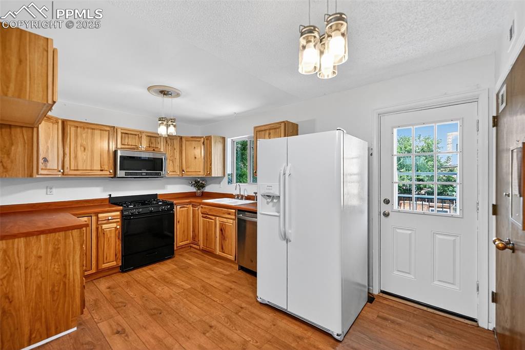 305 Iris Drive Fountain, CO 80817 - Photo 5 of 22 a kitchen with stainless steel appliances granite countertop a refrigerator a stove top oven a sink dishwasher and wooden cabinets