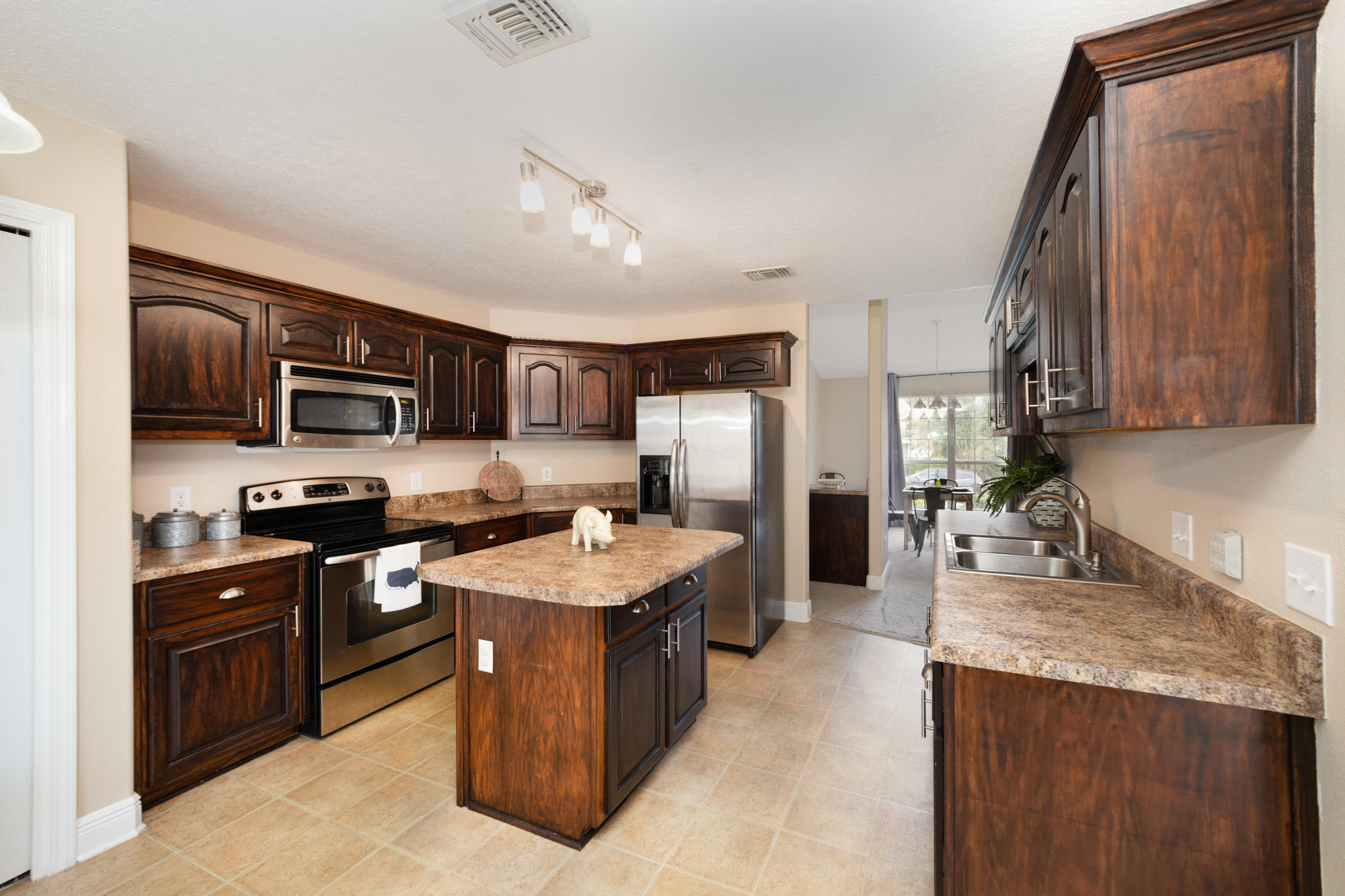 653 Territory Lane Crestview, FL 32536 - Photo 9 of 29 a large kitchen with stainless steel appliances granite countertop a stove top oven a sink dishwasher and a refrigerator with wooden cabinets