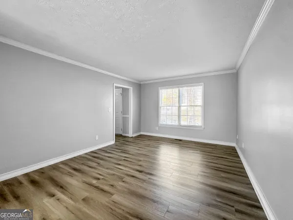 a view of an empty room with wooden floor and window