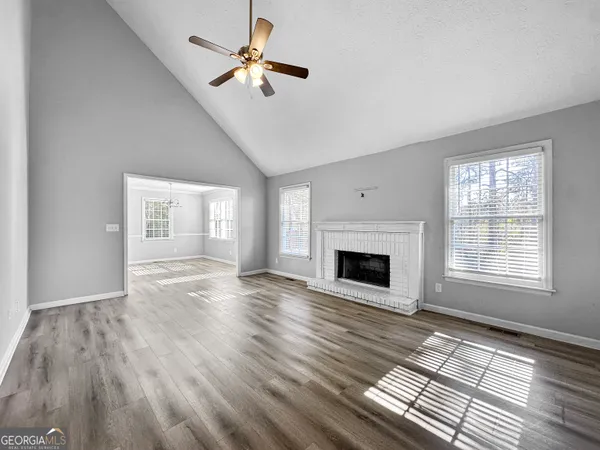 a view of an empty room with wooden floor fireplace and a window