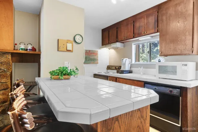 a kitchen with stainless steel appliances kitchen island granite countertop a sink a stove and a wooden cabinets