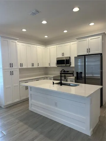a large kitchen with stainless steel appliances granite countertop a sink a stove and a refrigerator