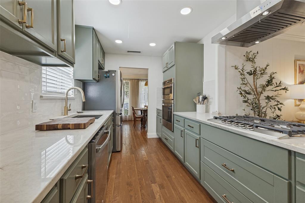 9864 Shoreview Road Dallas, TX 75238 - Photo 12 of 24 Galley kitchen featuring light green cabinetry, integrated stainless steel appliances, a gas range with a stainless steel vent hood, and wood-finish flooring