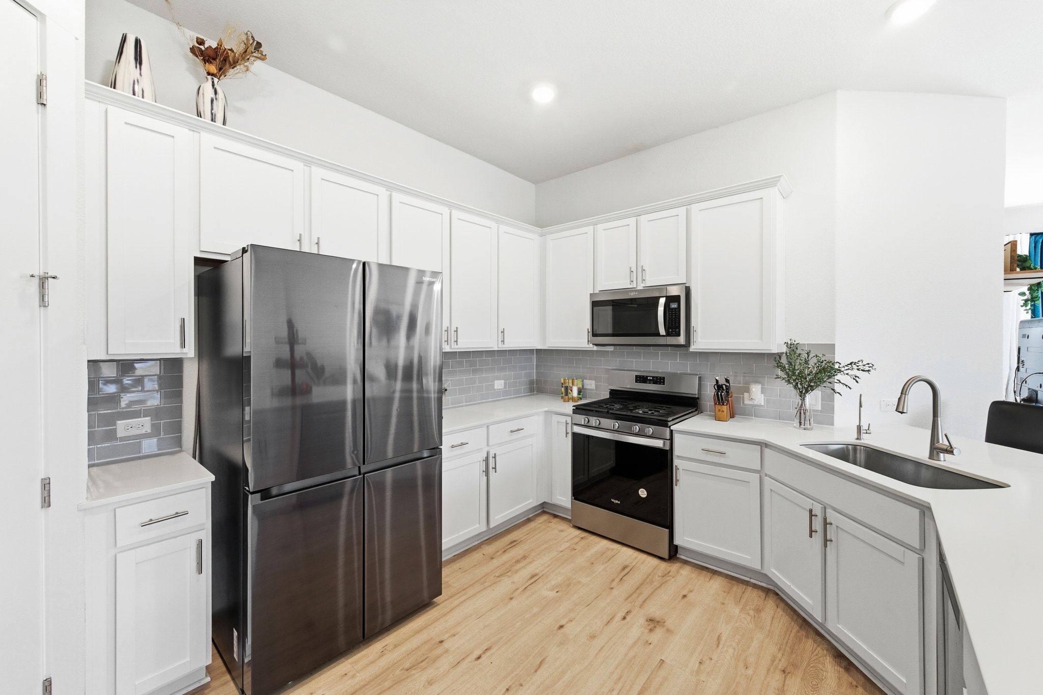 4420 Ingram Road Georgetown, TX 78628 - Photo 12 of 40 Kitchen with appliances with stainless steel finishes, white cabinetry, light wood-type flooring, tasteful backsplash, and recessed lighting