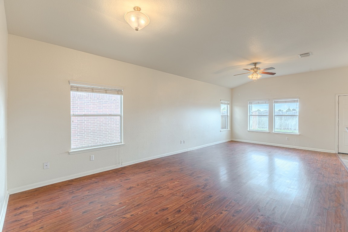 6526 Bella Noche Drive Spring, TX 77379 - Photo 12 of 46 an empty room with wooden floor chandelier fan and windows
