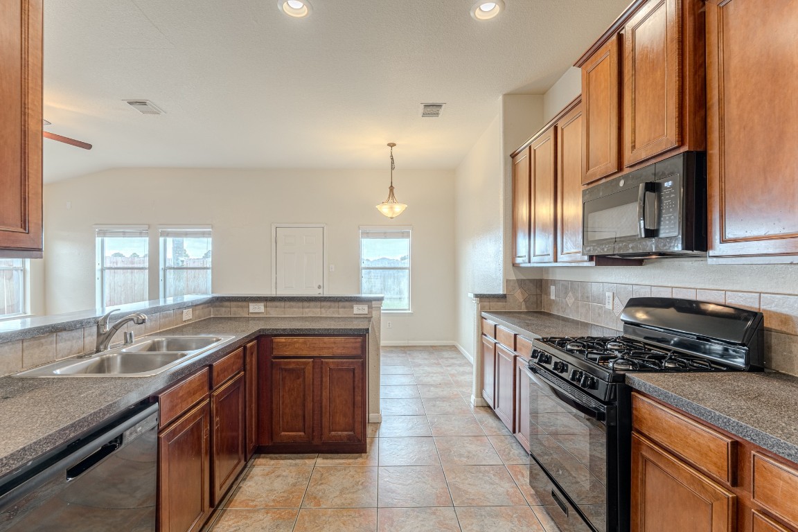 6526 Bella Noche Drive Spring, TX 77379 - Photo 18 of 46 a kitchen with stainless steel appliances granite countertop a sink stove and cabinets