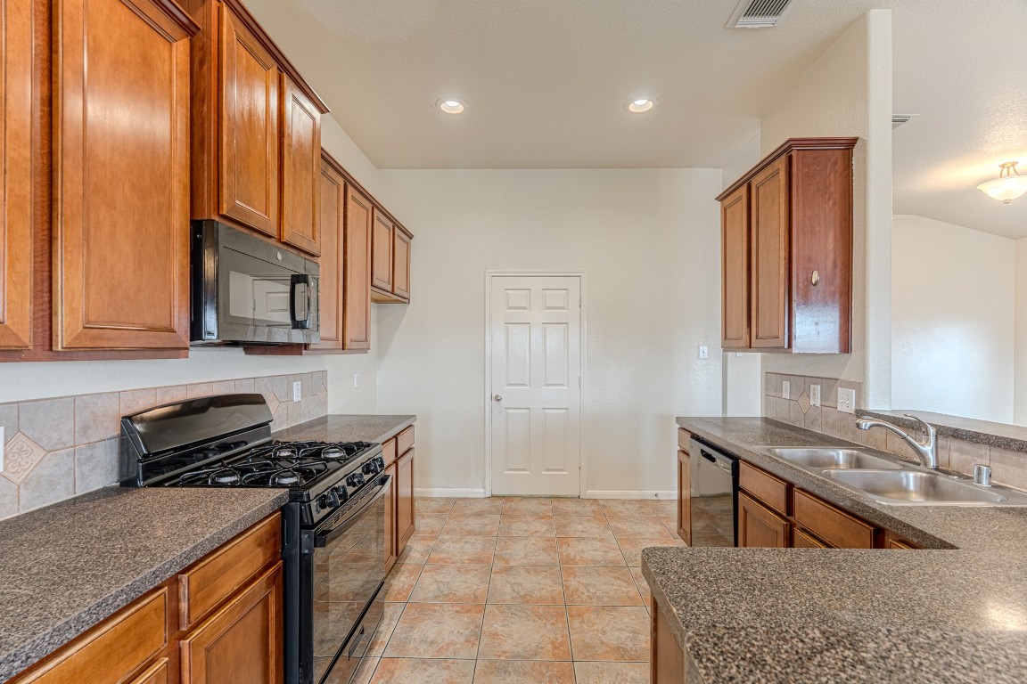 6526 Bella Noche Drive Spring, TX 77379 - Photo 21 of 46 a kitchen with stainless steel appliances granite countertop a stove a sink and a microwave