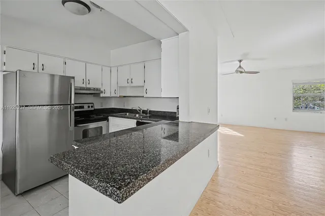 a kitchen with stainless steel appliances granite countertop a refrigerator a stove and a sink with wooden floor