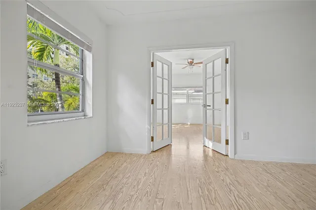 a view of an empty room with wooden floor and a window