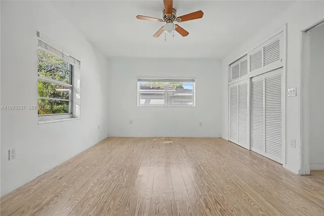 a view of an empty room with a window and wooden floor