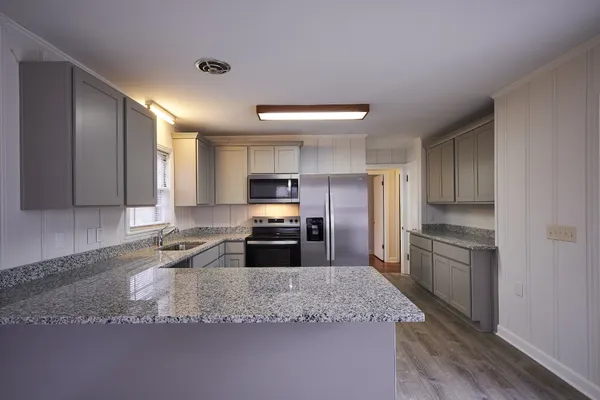 a kitchen with granite countertop stainless steel appliances a sink a stove a refrigerator cabinets and a counter top space