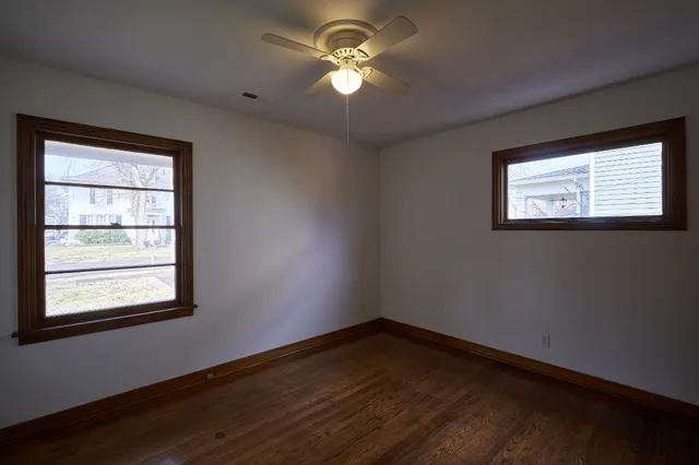 a view of empty room with wooden floor and fan