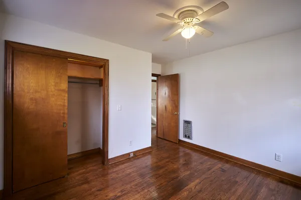 a view of an empty room with window and wooden floor