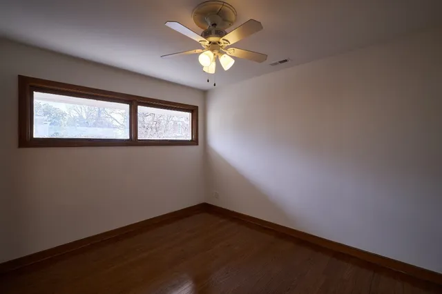 an empty room with windows and fan