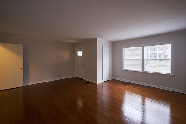 an empty room with wooden floor and windows