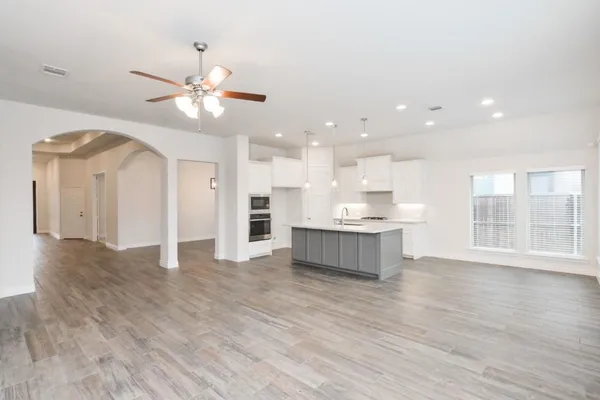 a view of kitchen with kitchen island stainless steel appliances refrigerator stove and wooden floor