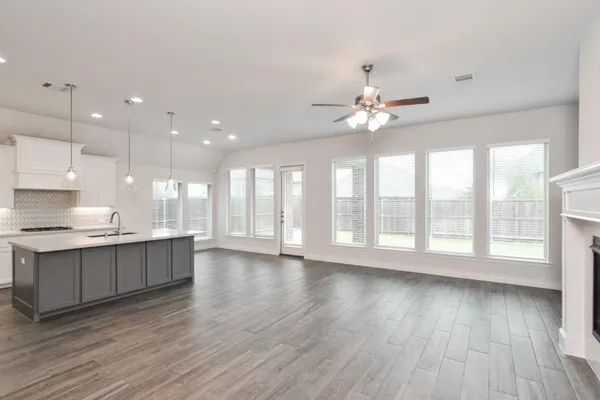 a large kitchen with granite countertop a stove a sink dishwasher and a fireplace with wooden floor