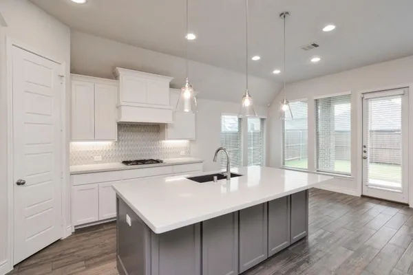 a kitchen with a sink a stove a refrigerator and white cabinets