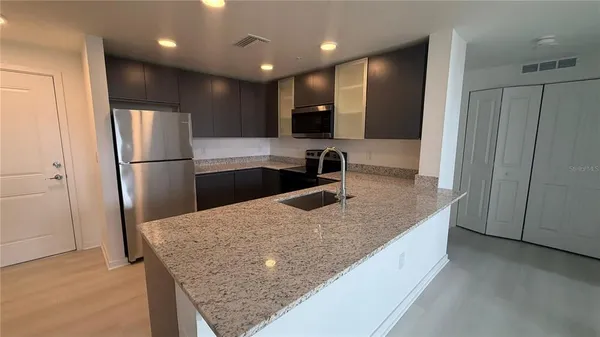 a kitchen with stainless steel appliances granite countertop a refrigerator a sink and a stove