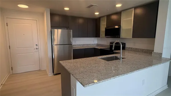 a kitchen with stainless steel appliances granite countertop a sink and a refrigerator