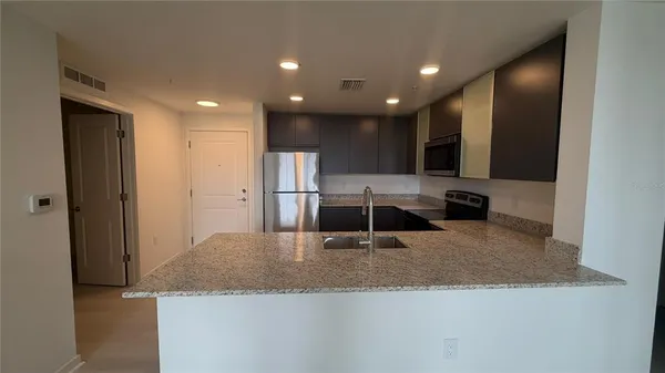 a kitchen with stainless steel appliances granite countertop a sink a refrigerator and a granite counter tops