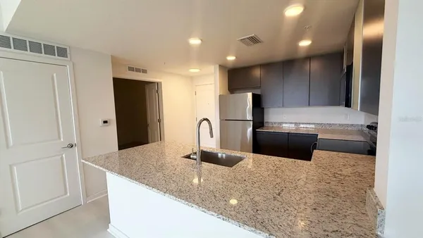 a kitchen with stainless steel appliances granite countertop a refrigerator a stove and a sink with wooden floor