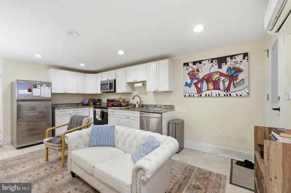 a living room with stainless steel appliances furniture and a kitchen view
