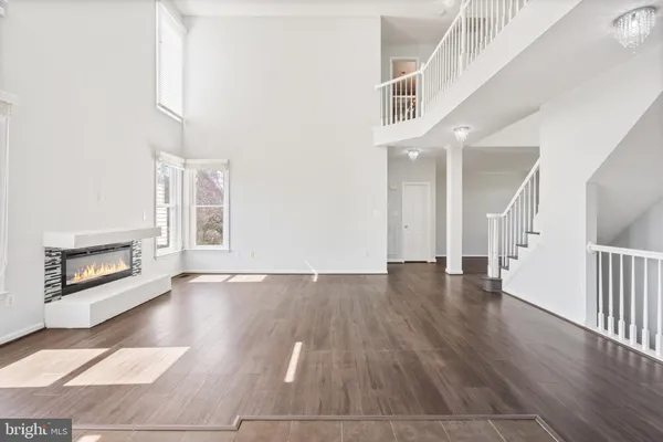 an empty room with wooden floor fireplace and windows