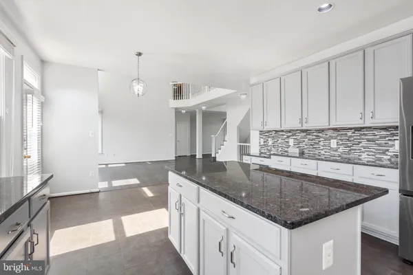 a kitchen with granite countertop a sink a counter top space and cabinets