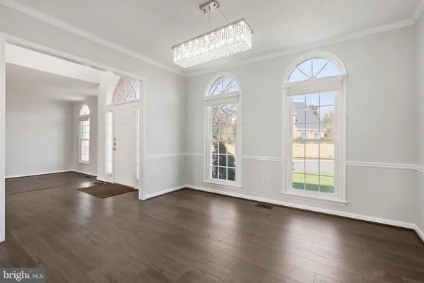 an empty room with wooden floor chandelier and windows