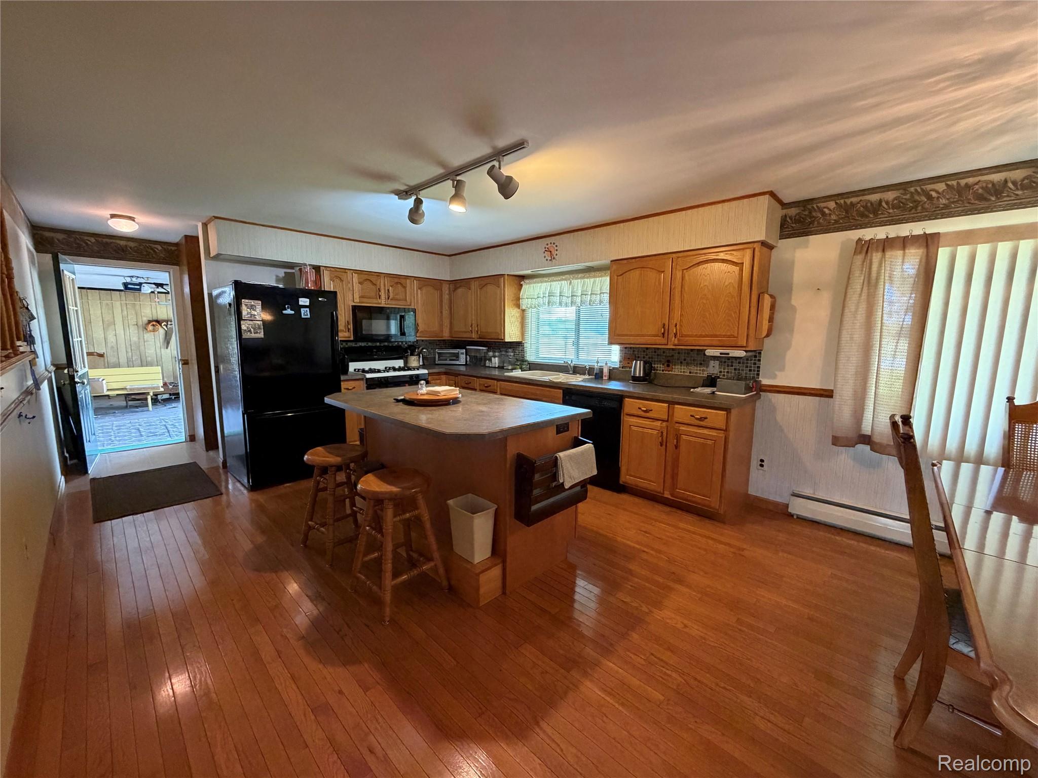 8886 East Burnside Road Brown City, MI 48416 - Photo 10 of 22 Kitchen featuring wood-finish flooring, a central island with a countertop, wood cabinetry, track lighting, and a window with vertical blinds