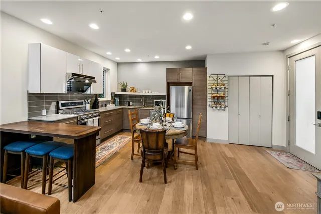 a kitchen with stainless steel appliances granite countertop a table chairs sink refrigerator and microwave