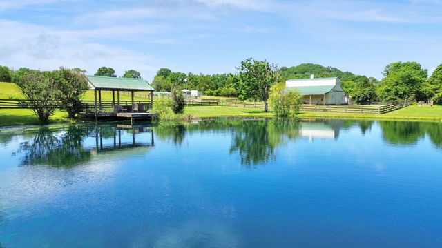 a kitchen with stainless steel appliances granite countertop a refrigerator a sink dishwasher a oven and a dining table with wooden floor