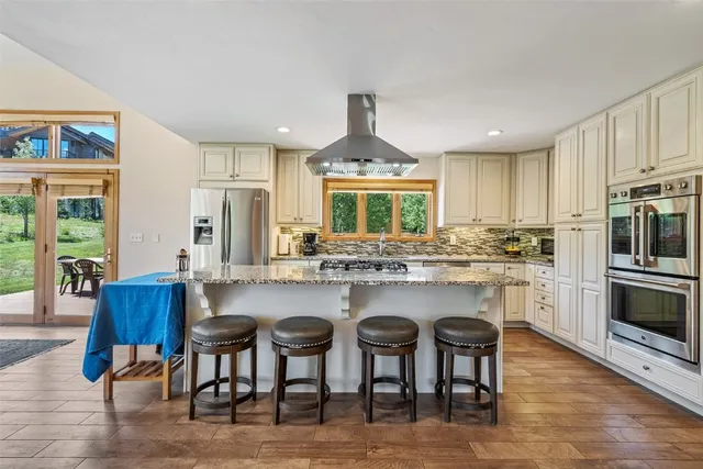 a kitchen with stainless steel appliances granite countertop a stove a sink a oven a dining table and chairs