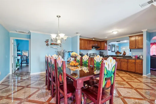 a dining room filled chandelier and kitchen view