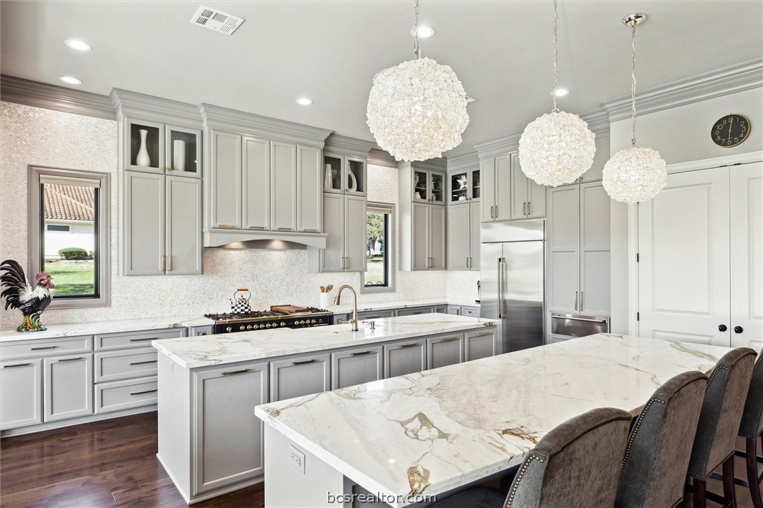 5202 Bourrone Court Bryan, TX 77802 - Photo 15 of 43 Kitchen featuring 2 islands, 3 high end pendent light, farm house sink and appliances with stainless steel finishes.