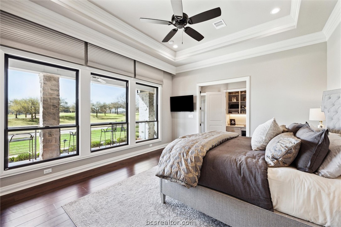 5202 Bourrone Court Bryan, TX 77802 - Photo 23 of 43 Primary Bedroom with raised tray ceiling, and crown molding looking out at Lake Heron and T-Box #9 with voice controlled shades for privacy