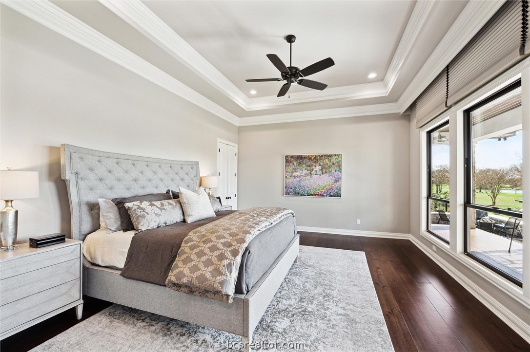5202 Bourrone Court Bryan, TX 77802 - Photo 24 of 43 Primary Bedroom with raised tray ceiling, and crown molding looking out at Lake Heron and T-Box #9