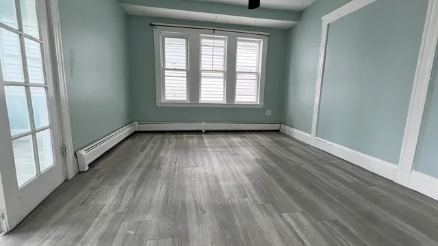 an empty room with wooden floor and windows
