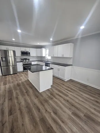 a kitchen with stainless steel appliances granite countertop a white cabinets counter top space and a center island