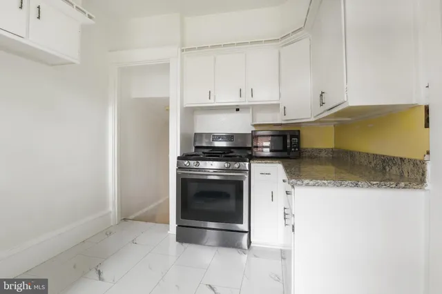 a kitchen with granite countertop white cabinets and stainless steel appliances