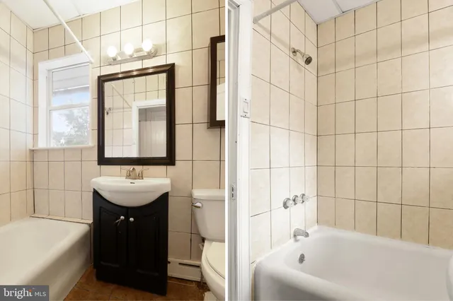 a bathroom with a sink a bathtub and next to a window