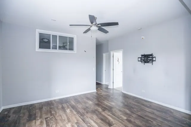 a view of empty room with wooden floor and ceiling fan