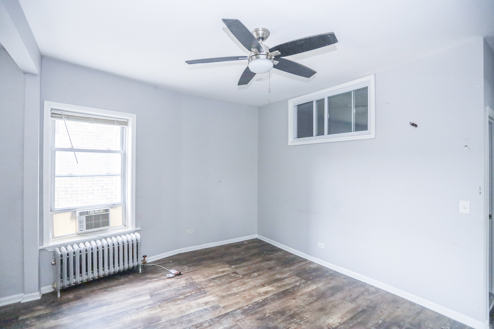 4400 North Magnolia Avenue, Unit 321 Chicago, IL 60640 - Photo 7 of 12 an empty room with wooden floor windows and fan