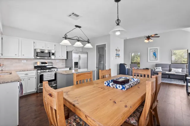 a kitchen with stainless steel appliances granite countertop a stove a sink dishwasher a dining table and chairs with wooden floor