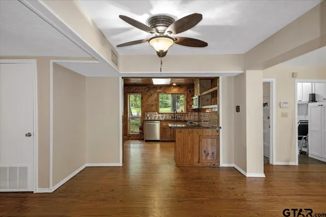 a view of a livingroom with a ceiling fan & hardwood floor