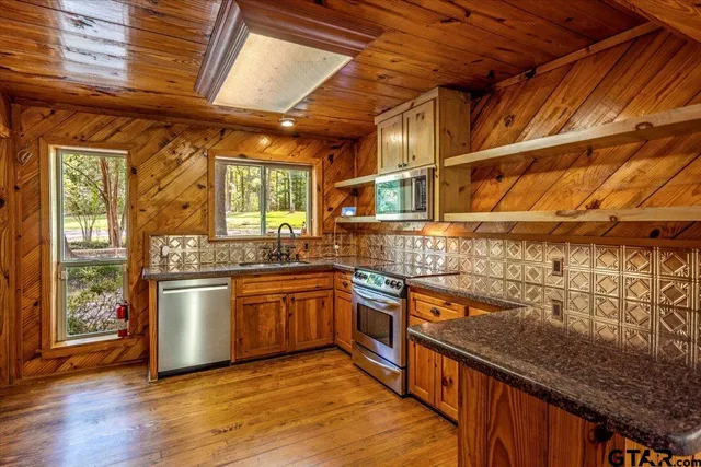a kitchen with stainless steel appliances granite countertop lots of counter top space and wooden floor