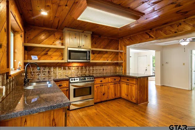 a kitchen with stainless steel appliances granite countertop a stove a sink and a microwave